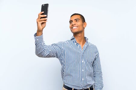 Young handsome brunette man over isolated blue background making a selfieの写真素材