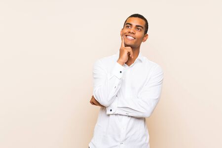 Young handsome brunette man over isolated background thinking an idea while looking upの写真素材