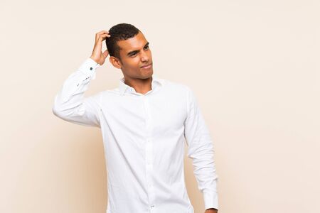 Young handsome brunette man over isolated background having doubts while scratching headの写真素材