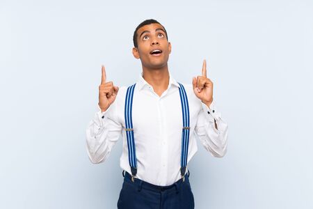 Young handsome brunette man with suspenders over isolated background pointing with the index finger a great ideaの写真素材