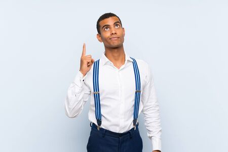 Young handsome brunette man with suspenders over isolated background pointing with the index finger a great ideaの写真素材