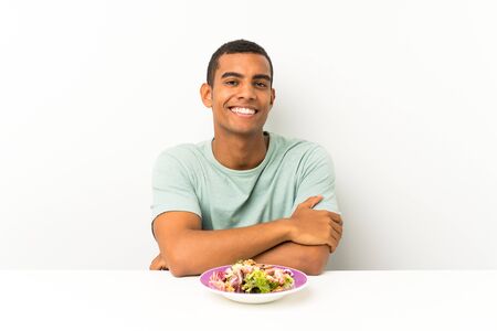 Young handsome man with salad in a table laughingの写真素材