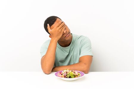 Young handsome man with salad in a table covering eyes by handsの写真素材