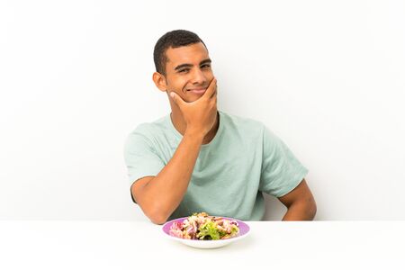 Young handsome man with salad in a table thinking an ideaの写真素材
