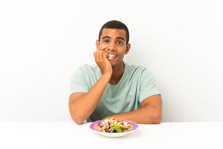 Young handsome man with salad in a table nervous and scaredの写真素材