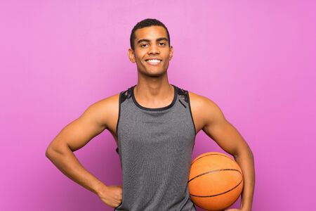 Young sport man with ball of basketball over isolated purple wallの写真素材