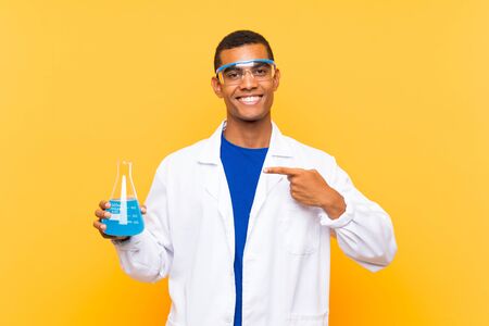 Scientific man holding a laboratory flask over isolated background and pointing itの写真素材