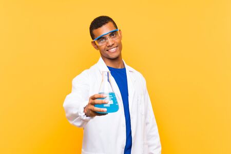 Scientific man holding a laboratory flask over isolated background with happy expressionの写真素材