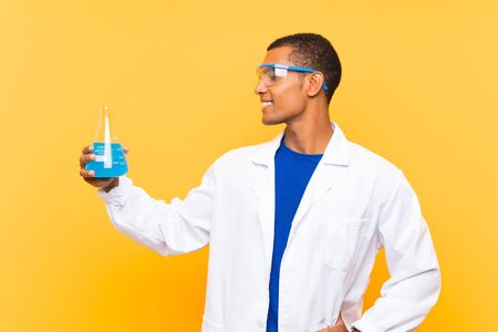 Scientific man holding a laboratory flask over isolated background with happy expressionの写真素材