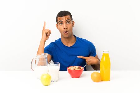 Young man having breakfast in a table with surprise facial expressionの写真素材
