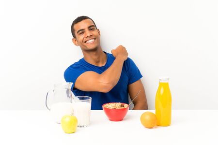 Young man having breakfast in a table celebrating a victoryの写真素材