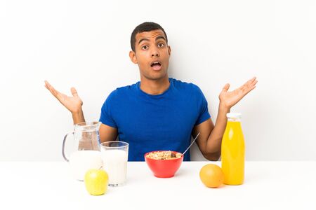 Young man having breakfast in a table with surprise facial expressionの写真素材
