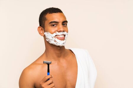 Young handsome man shaving his beard over isolated background smiling a lotの写真素材