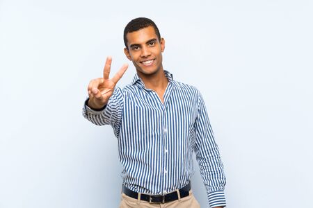 Young handsome brunette man over isolated blue background smiling and showing victory signの写真素材