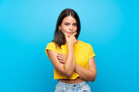 Young girl over isolated blue background thinkingの写真素材