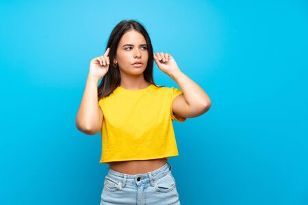 Young girl over isolated blue background having doubts and thinkingの写真素材