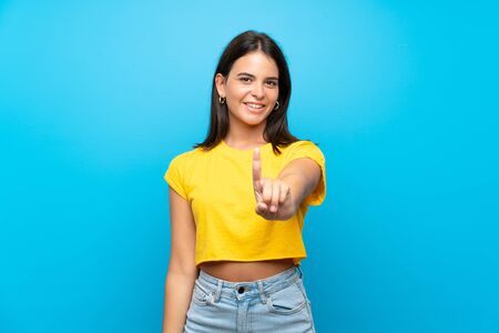 Young girl over isolated blue background showing and lifting a fingerの写真素材