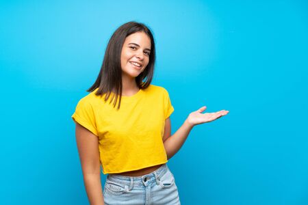 Young girl over isolated blue background presenting an idea while looking smiling towardsの写真素材