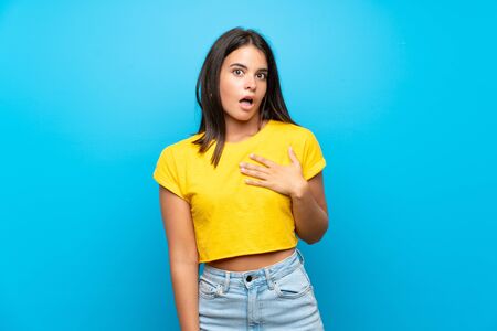 Young girl over isolated blue background surprised and shocked while looking rightの写真素材
