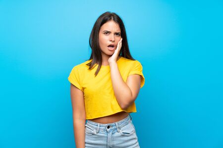 Young girl over isolated blue background surprised and shocked while looking rightの写真素材