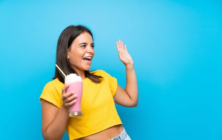 Young girl with strawberry milkshake over isolated background with surprise facial expressionの写真素材