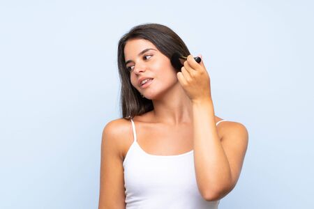 Young girl holding makeup brush over isolated backgroundの写真素材