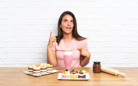 Young girl with lots of different mini cakes with surprise facial expressionの写真素材