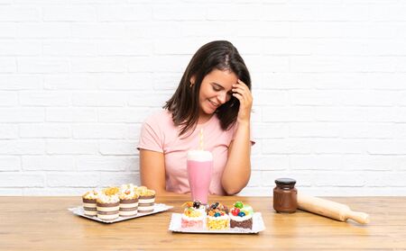Young girl with lots of different mini cakes laughingの写真素材
