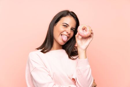 Young girl holding a donut over isolated pink backgroundの写真素材