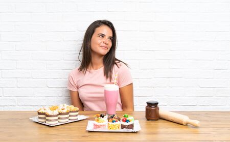 Young girl with lots of different mini cakes laughing and looking upの写真素材