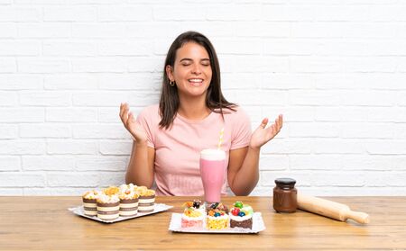 Young girl with lots of different mini cakes laughingの写真素材