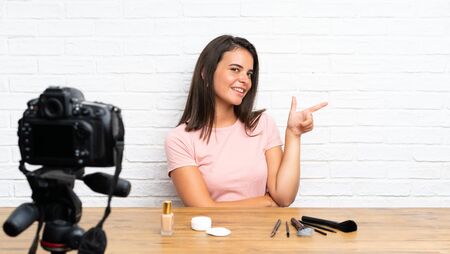 Young girl recording a video tutorial pointing finger to the sideの写真素材