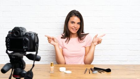 Young girl recording a video tutorial pointing to the laterals having doubtsの写真素材
