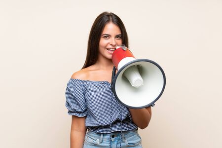 Young girl over isolated background shouting through a megaphoneの写真素材