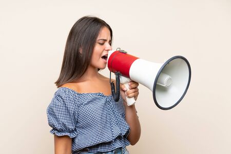 Young girl over isolated background shouting through a megaphoneの写真素材