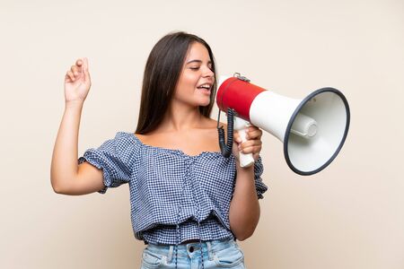 Young girl over isolated background shouting through a megaphoneの写真素材