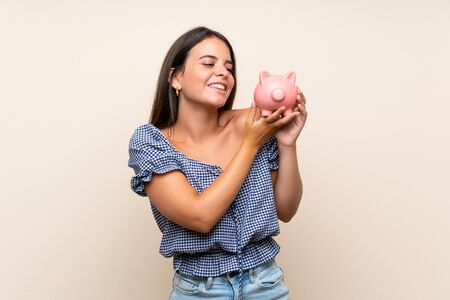 Young girl over isolated background holding a big piggybankの写真素材