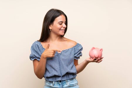 Young girl over isolated background holding a big piggybankの写真素材