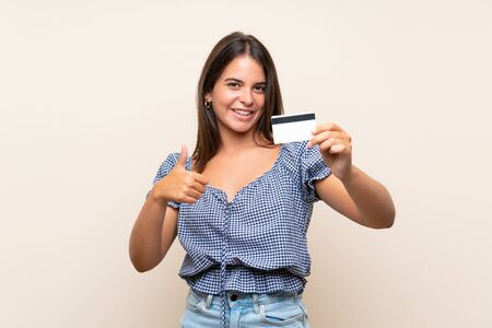 Young girl over isolated background holding a credit cardの写真素材