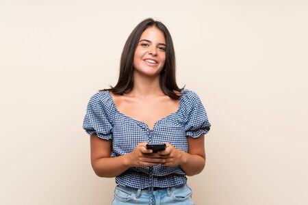 Young girl over isolated background using mobile phoneの写真素材