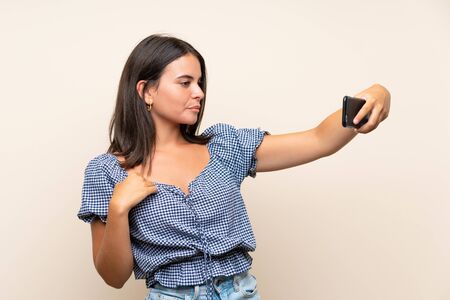 Young girl over isolated background making selfie with cellphoneの写真素材