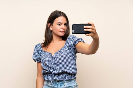Young girl over isolated background making selfie with cellphoneの写真素材