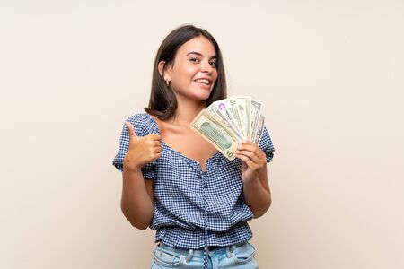 Young girl over isolated background taking a lot of moneyの写真素材