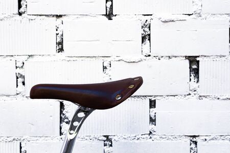 Isolated saddle of an old fixed gear bicycle in a white brick wall. Horizontal photography. Hipster...