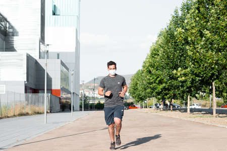 Granada, Spain, July 10, 2020: Handsome man in medical mask running outdoors. Coronavirus pandemic situation.のeditorial素材
