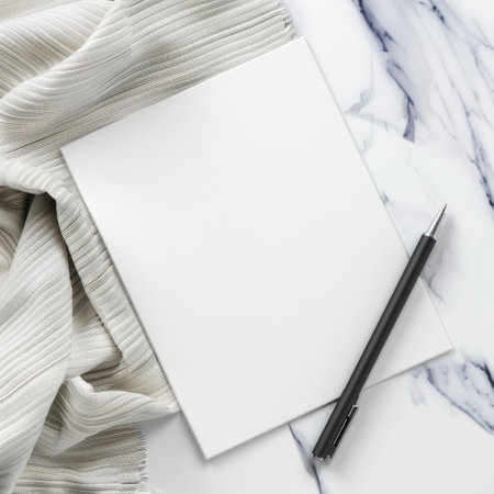 A notebook and pen are placed neatly on a sleek marble surface. The notebook is open, revealing blank pages waiting to be filled with ideas and notes. The pen is positioned next to the notebook, ready to be picked up for writing.の素材