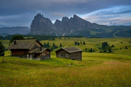 Sassolungo mountains on the Italian Alps Dolomites with wood houses on the foregroundの写真素材