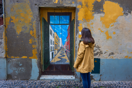 Girl Woman Traveler looking at a painted door on a traditional street in Funchal, Madeiraの写真素材