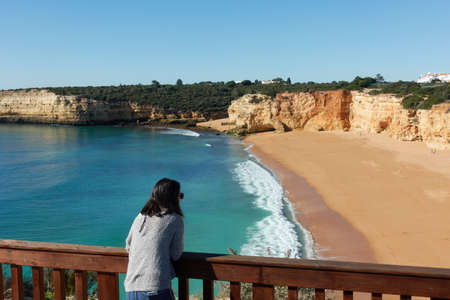 Woman looking at Nossa Senhora da Rocha beach in Algarve at sunset, Portugalの写真素材