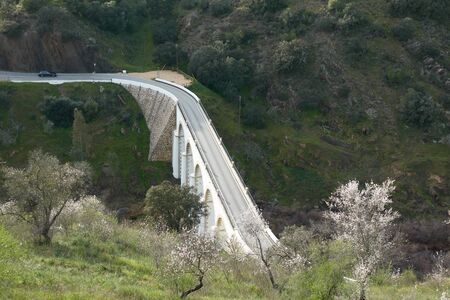 Mertola beautiful white and stone bridge on the city entrance with almond trees on the landscape in...